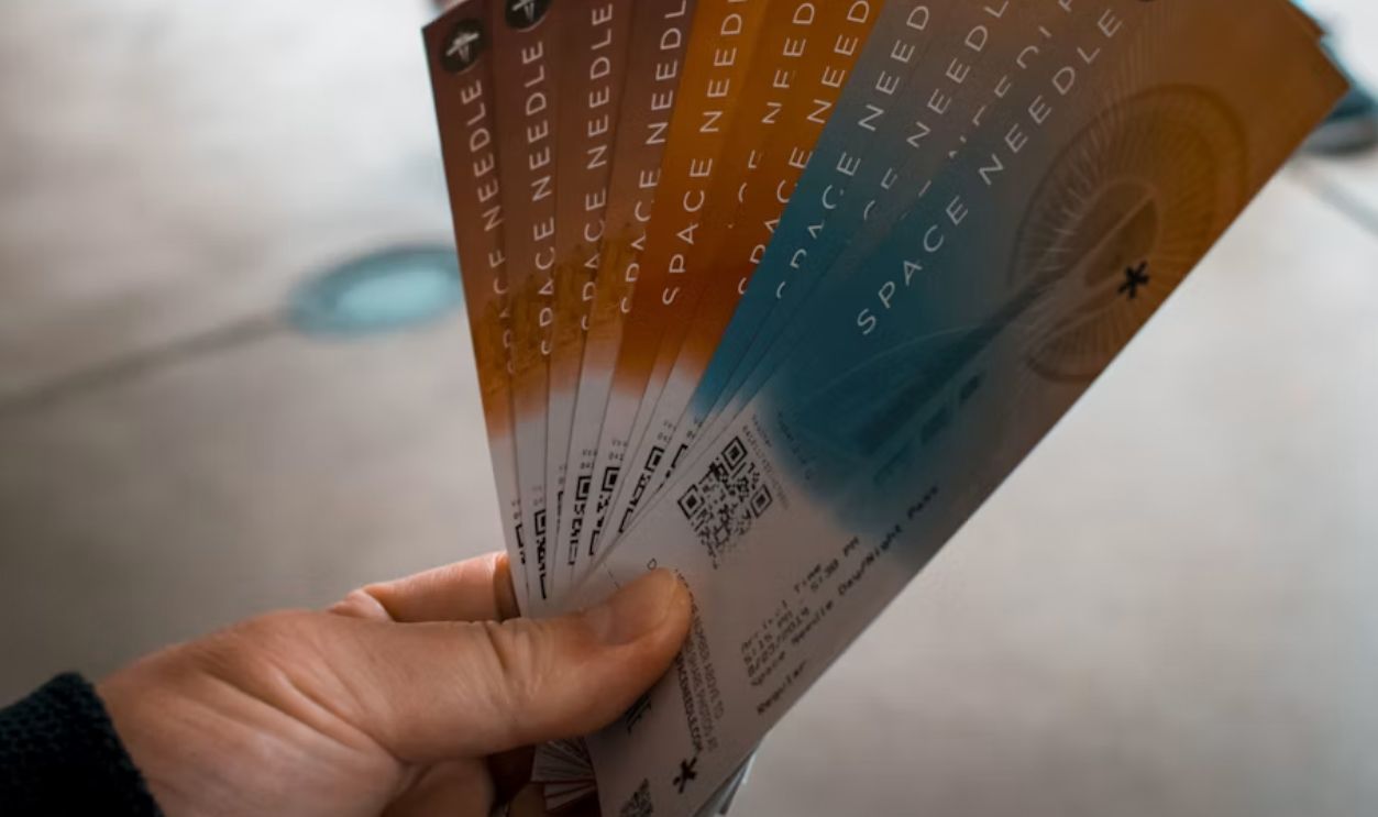 person holding brown, blue, and white tickets