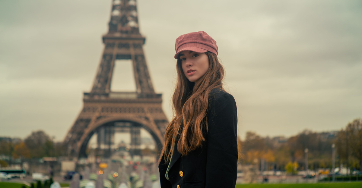 Young woman in a pink cap and black coat poses near the Eiffel Tower in Paris.