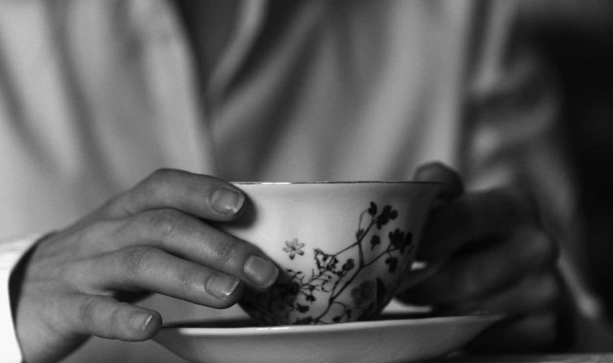 Elegant monochrome shot of hands holding a cup with floral design