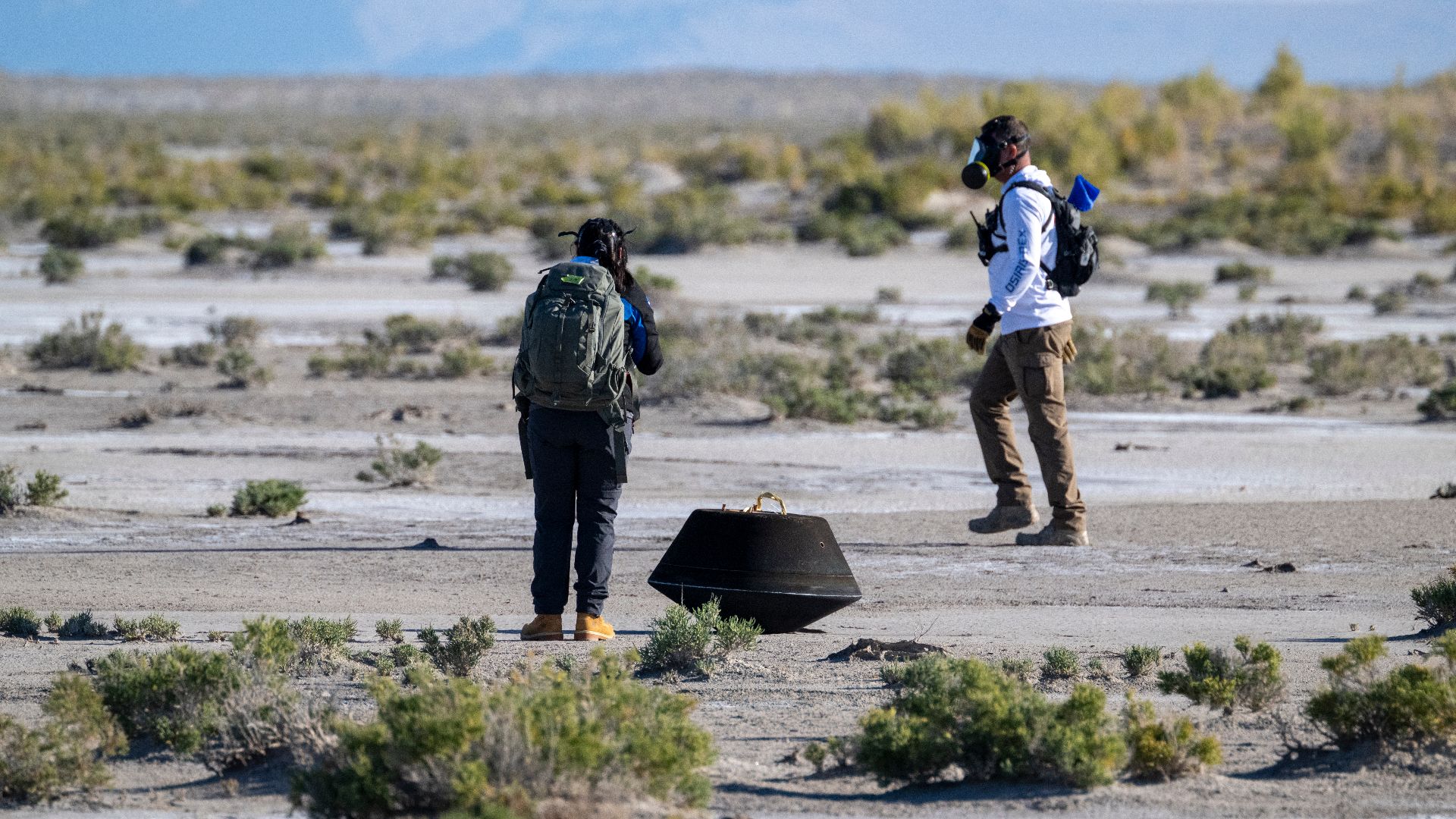 Lockheed Martin System Safety Engineer Victoria Thiem, left, and On Scene Commander of Recovery Stuart Wylie, right, perform preliminary checks on the sample return capsule from NASA’s OSIRIS-REx mission, Sunday, Sept. 24, 2023, shortly after the capsule 