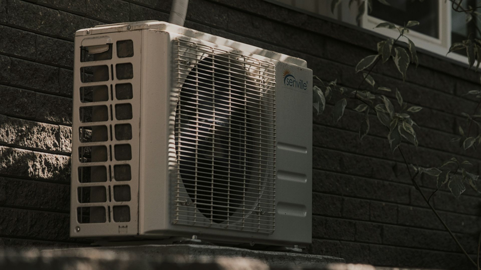 a white air conditioner sitting on top of a brick wall