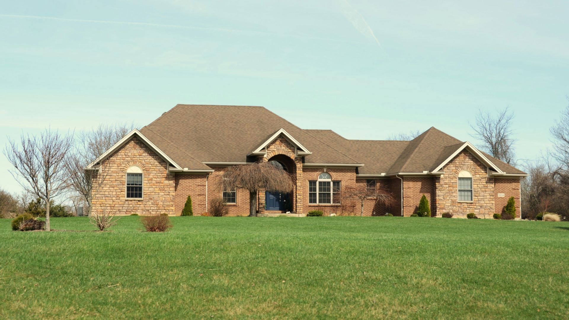 A large brick house with a manicured lawn.