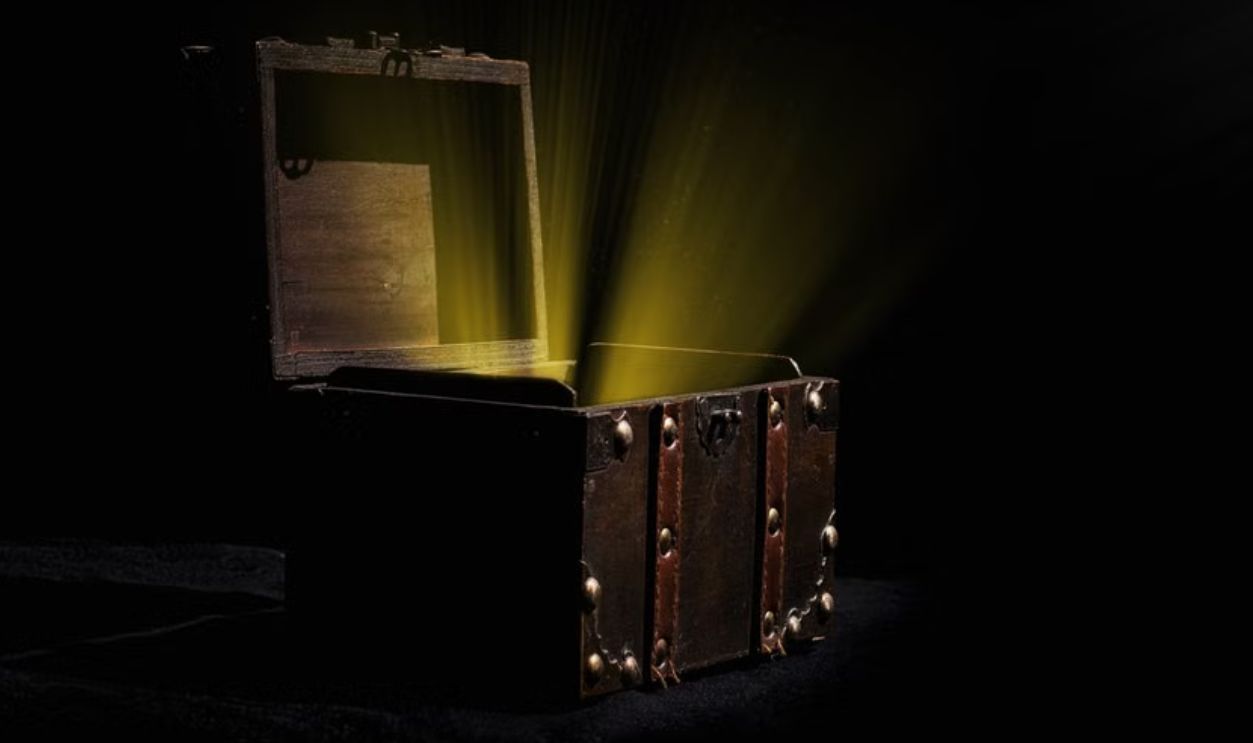 Open wooden chest emitting a mysterious glowing light in a dark room