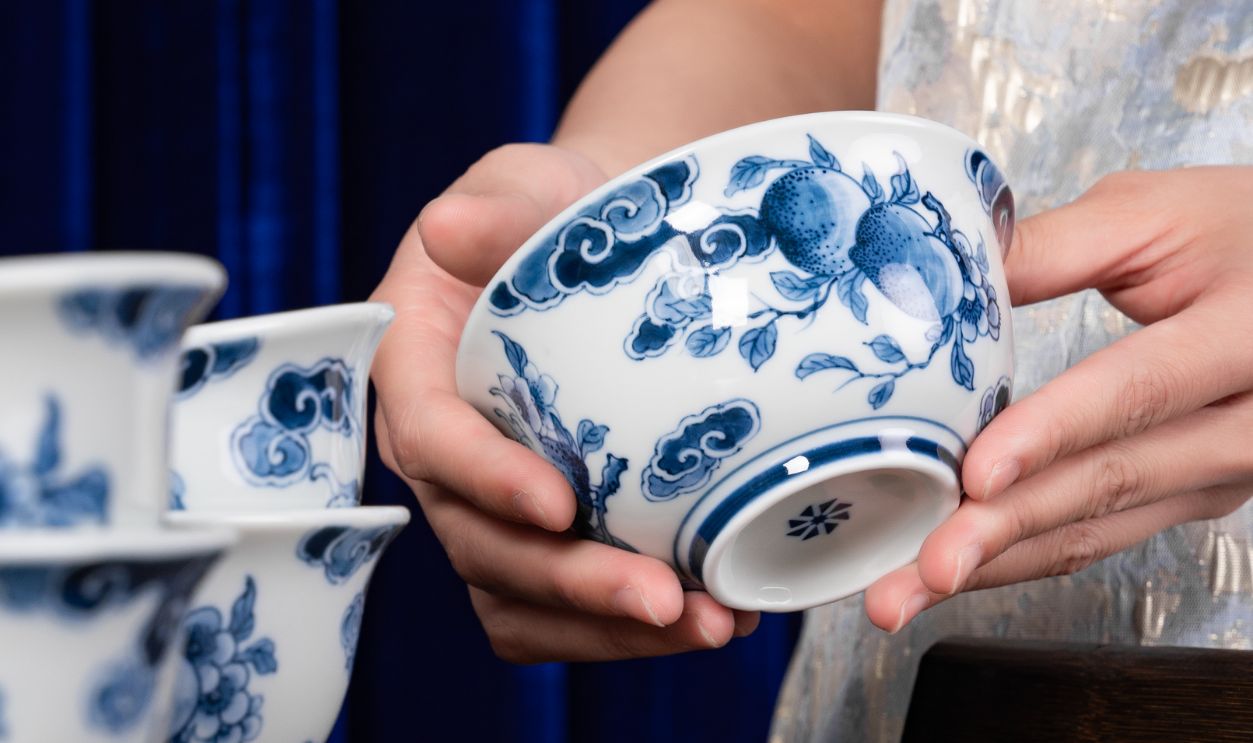 Close-up of hands holding decorative blue and white ceramic bowls on a wooden table