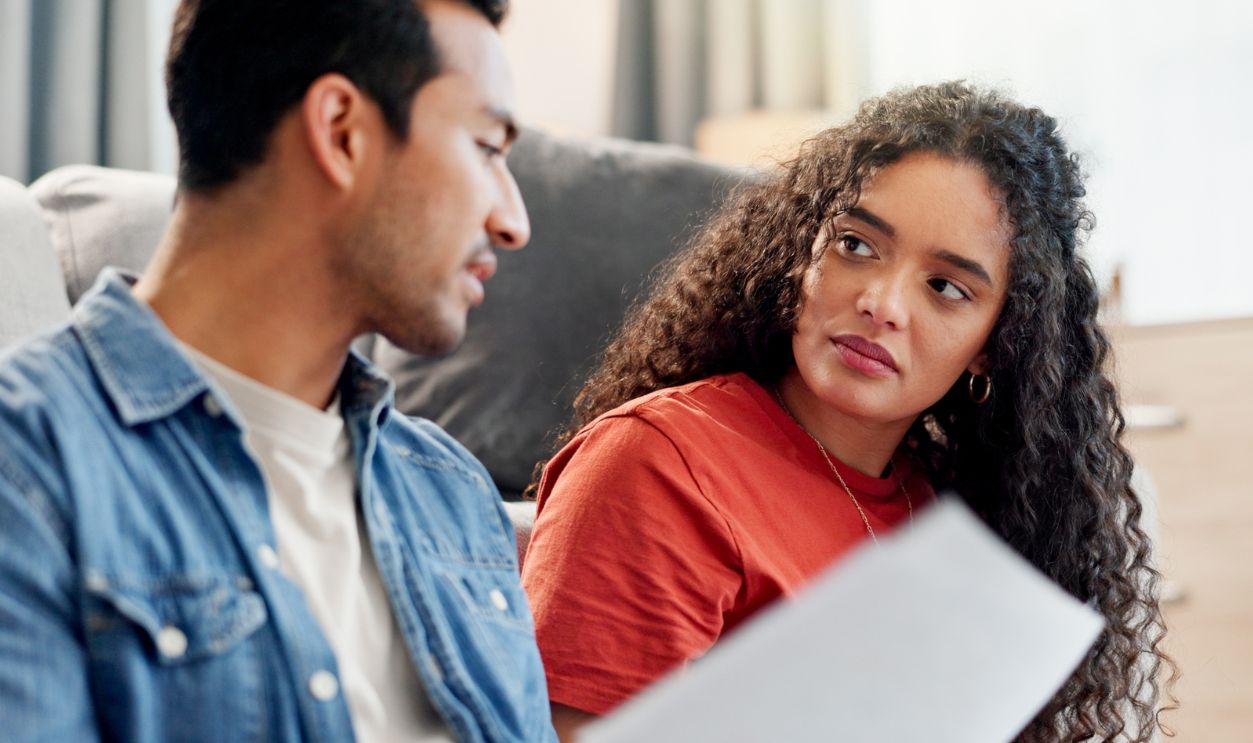 Serious, couple and talking with document at house for finance planning, payment error and bankruptcy. People, listening and laptop for loan paperwork, budget mistake and worry for home repossession