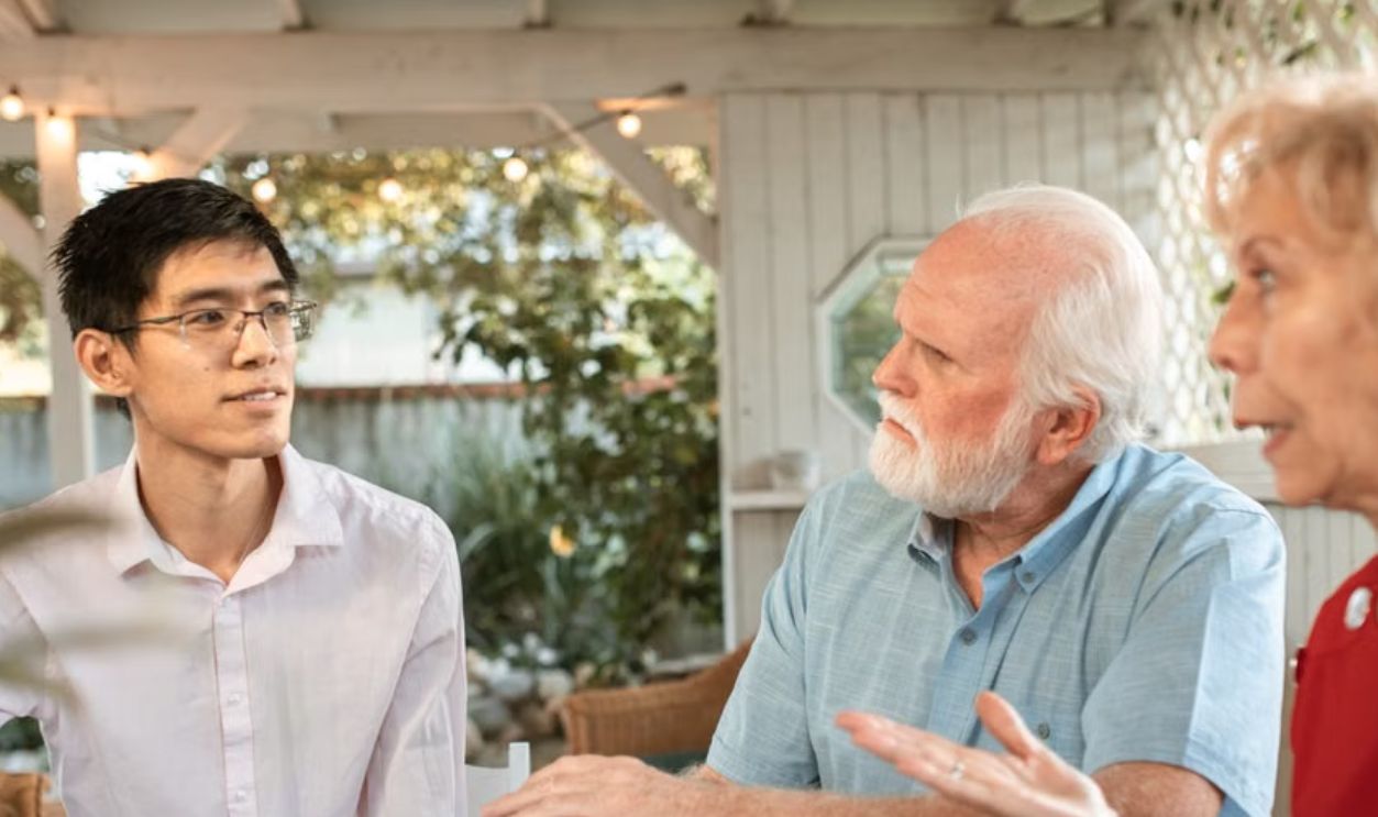 Senior couple and family member discussing ultrasound photos at an outdoor table
