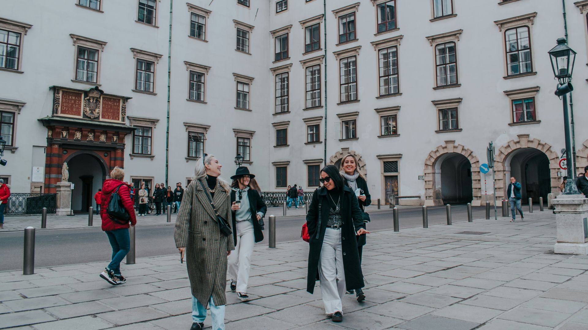 a group of people walking down a street next to tall buildings