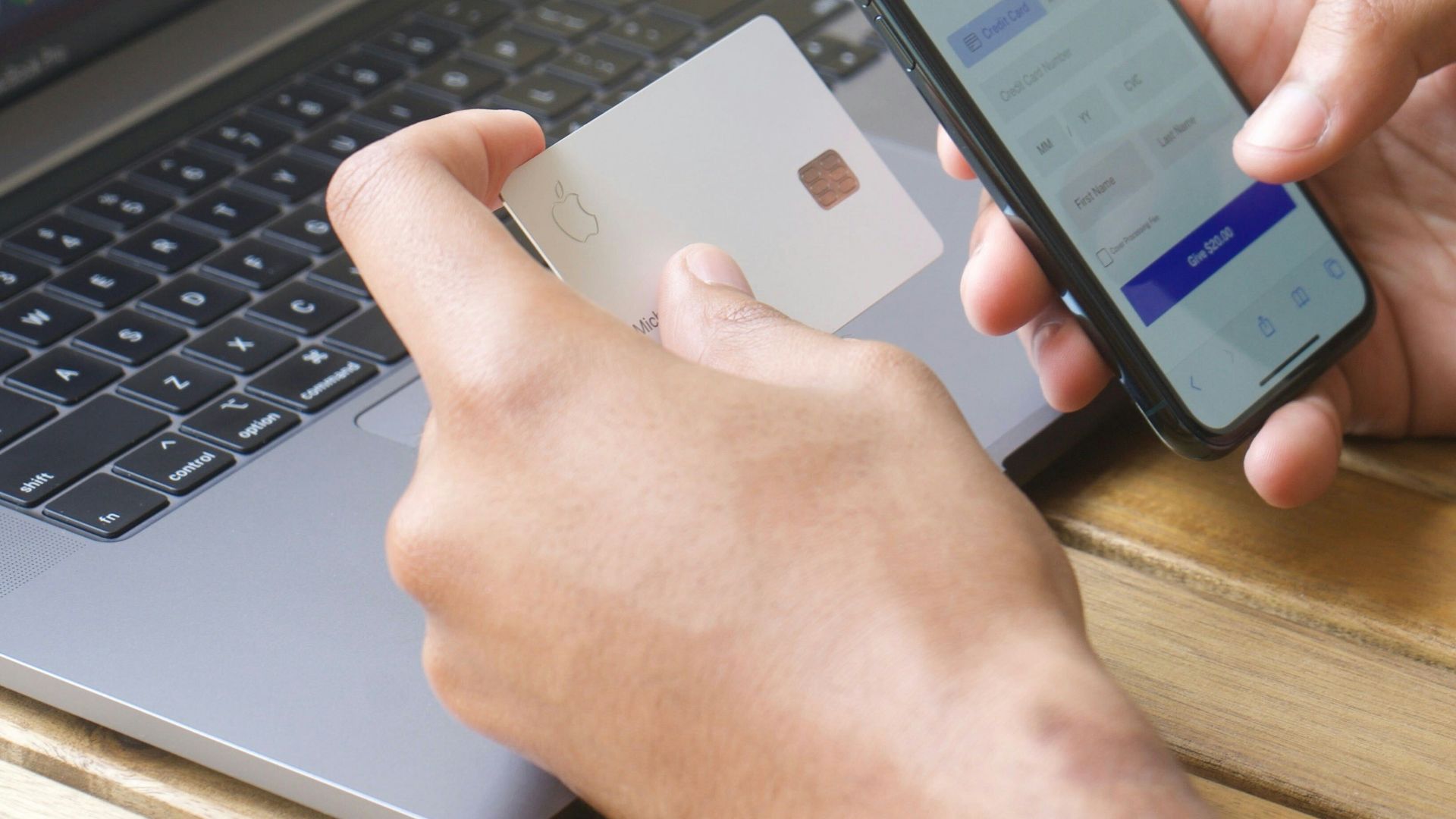 Person using smartphone and credit card with laptop