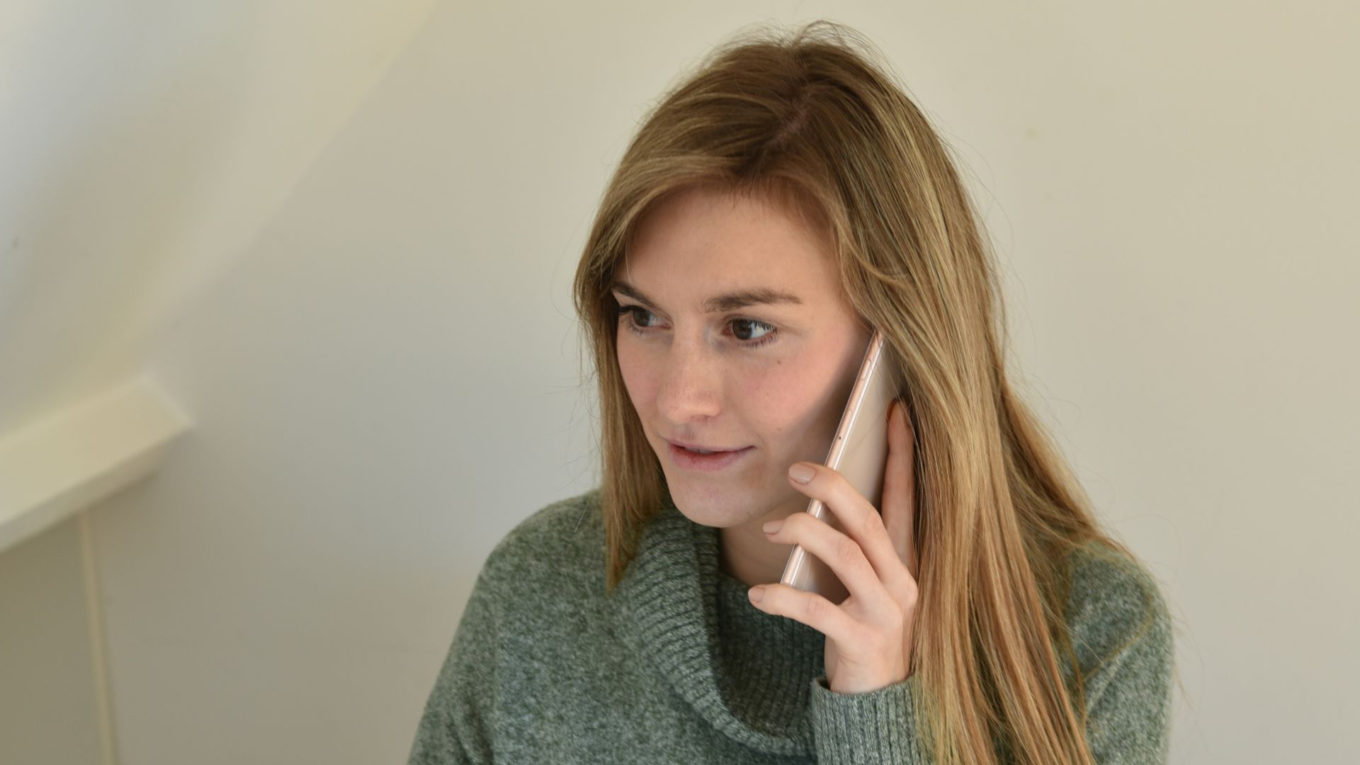 a woman sitting in front of a computer talking on a cell phone