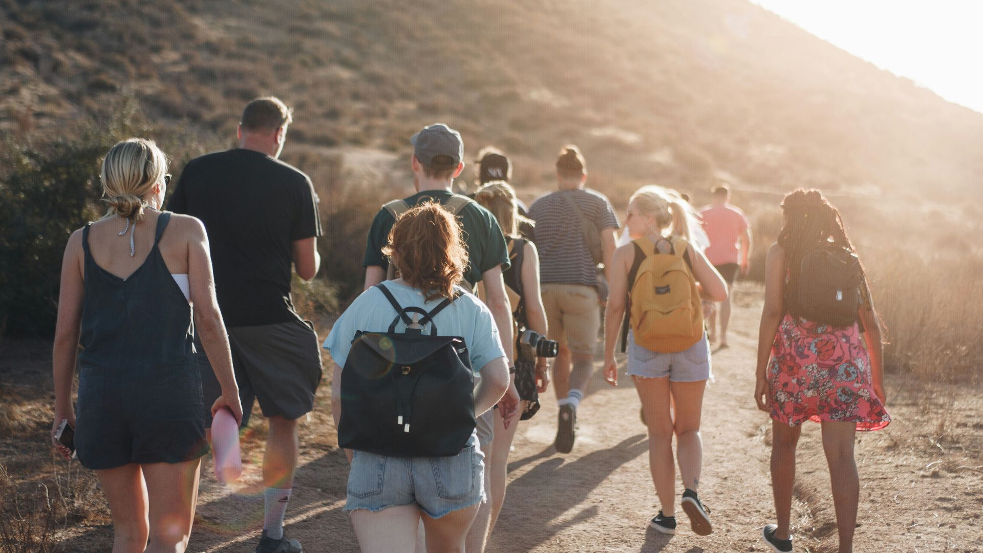 people walking on dirt road near mountain during daytime