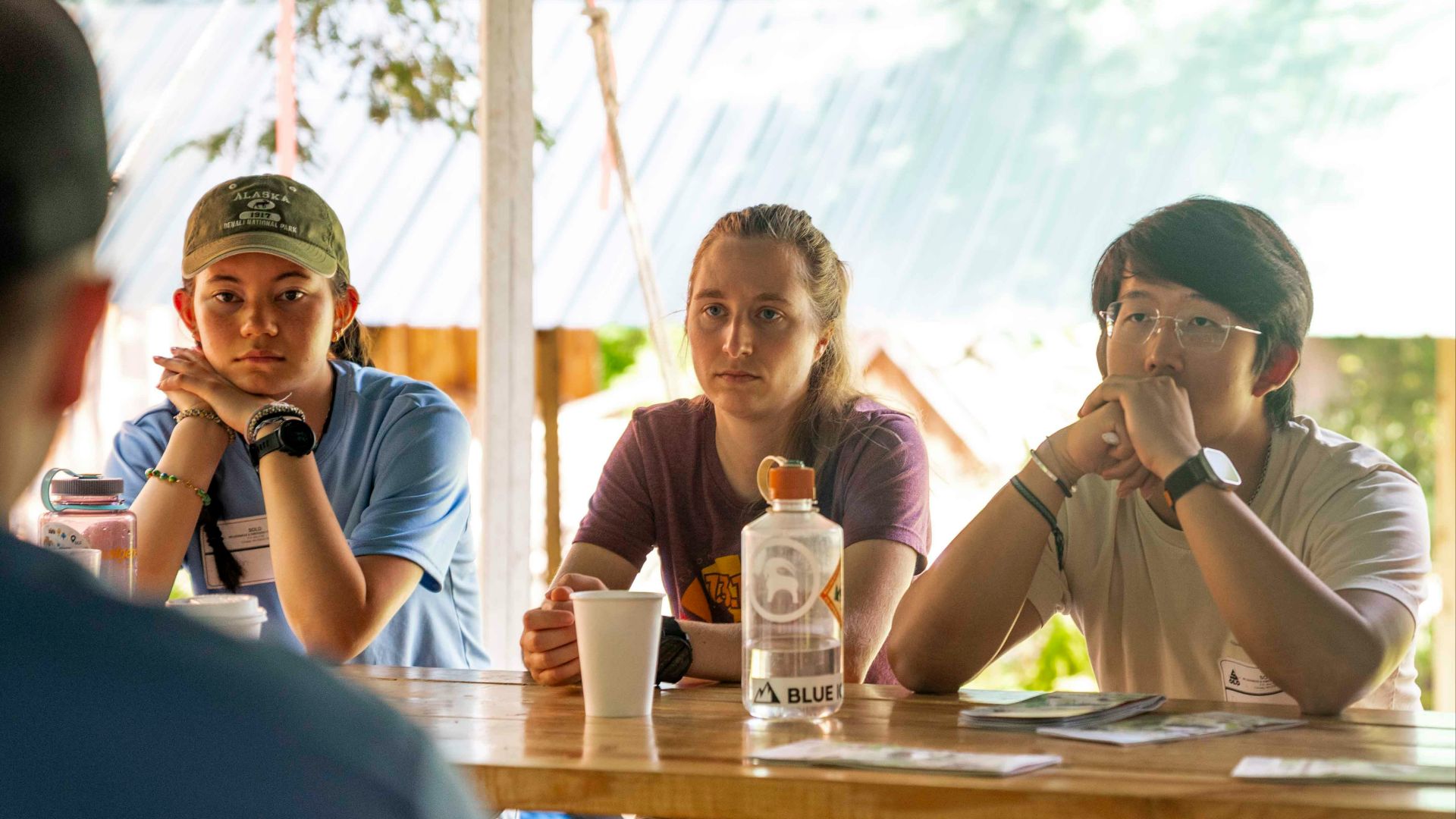 Three young people attentively listening at a table.