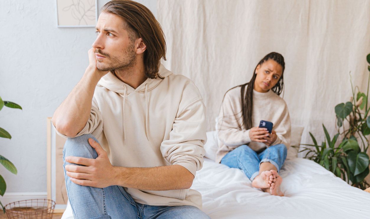 Contemplative couple in a cozy bedroom with natural lighting and minimal decor