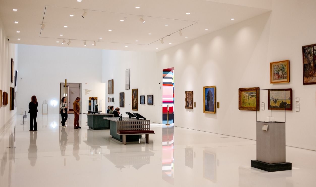 Spacious modern art museum with visitors browsing paintings