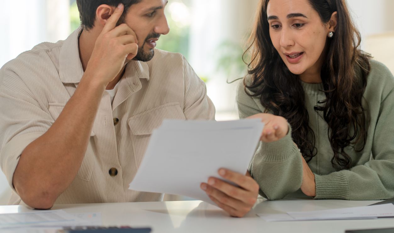 Finance and family paperwork. Hispanic Latin Couple checking bank account, financial statements and reports, doing online banking on laptop with documents at home