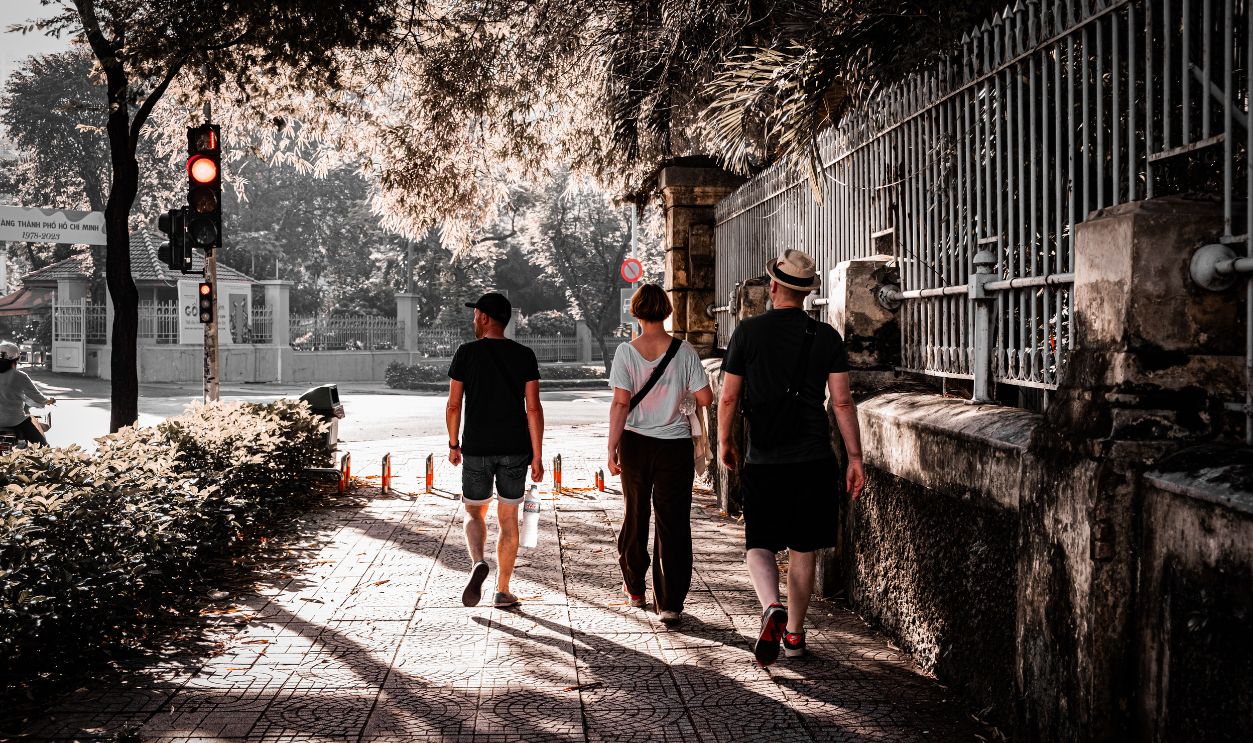 Three adults stroll down a shaded urban walkway