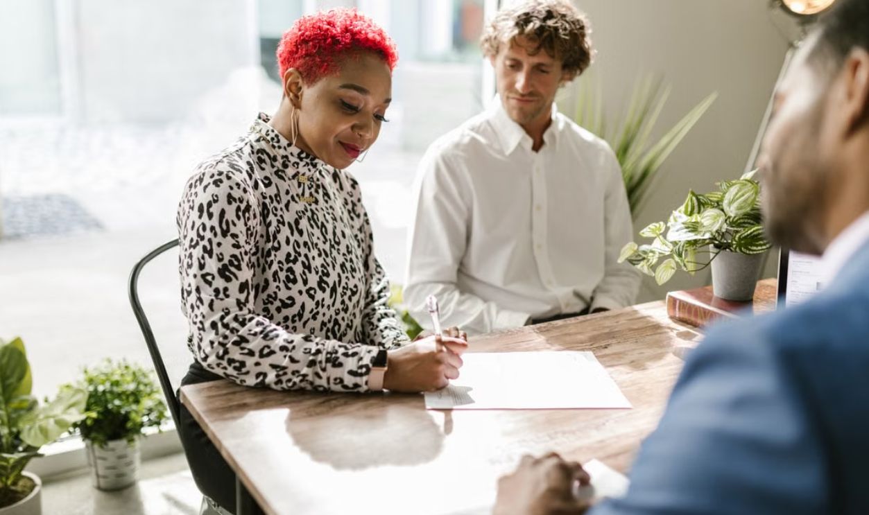A professional signing documents during a meeting in a modern office space