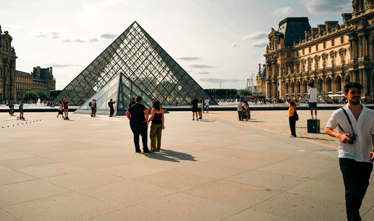 A daytime view of the Louvre Pyramid in Paris with people