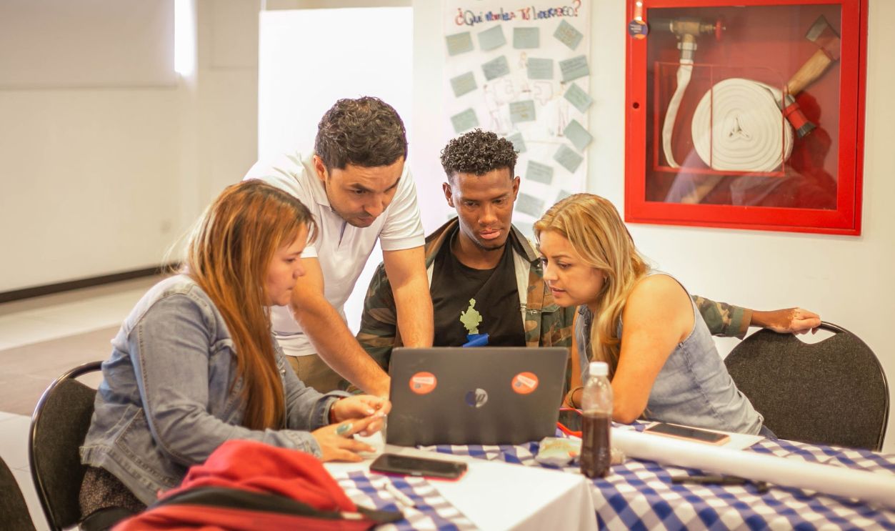 A diverse group of adults collaborating around a laptop during a team meeting in a professional setting