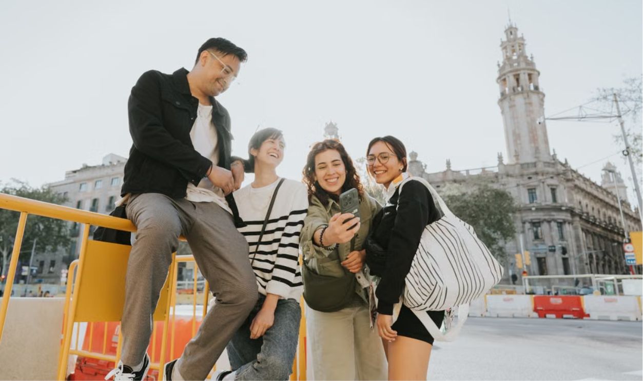 Happy group of friends taking a selfie outdoors near historic buildings in Barcelona, Spain