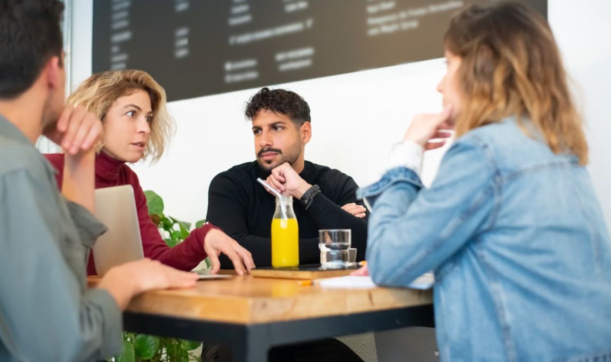 A group engaged in a thoughtful discussion at a trendy café in Portugal, fostering creativity