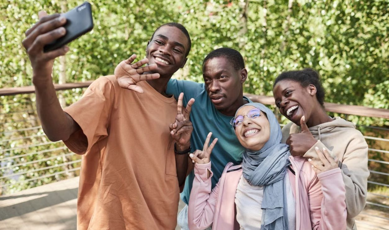 Diverse group of friends enjoying a selfie in a sunny park, showcasing joy and friendship