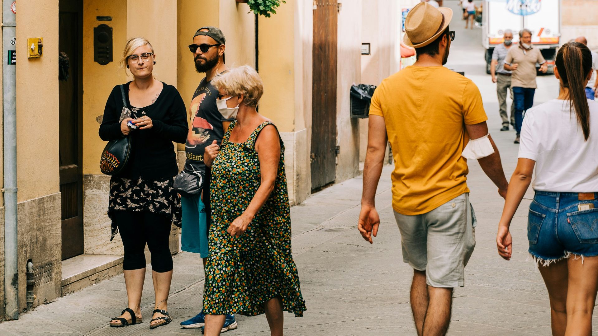 man in orange crew neck t-shirt standing beside woman in black and white floral dress