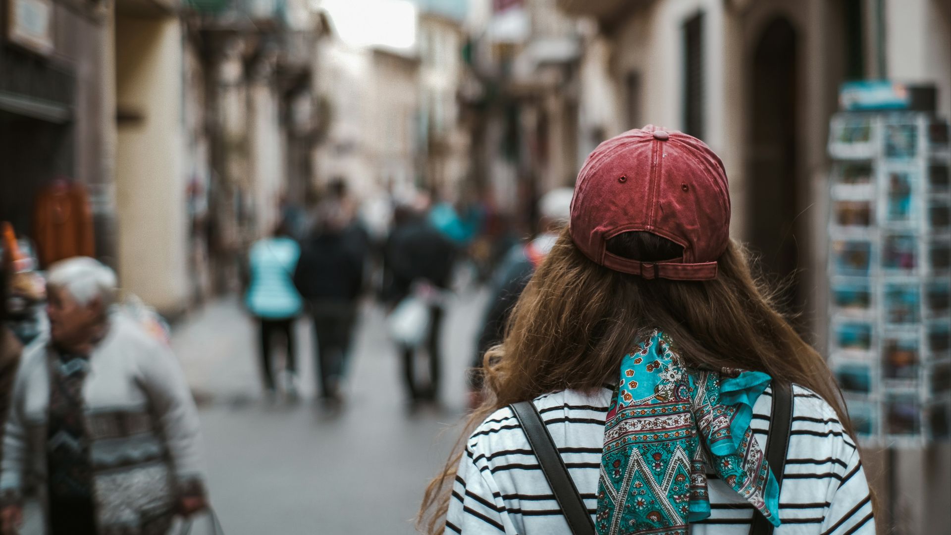 woman in red knit cap and blue and white tribal print shirt walking on street during