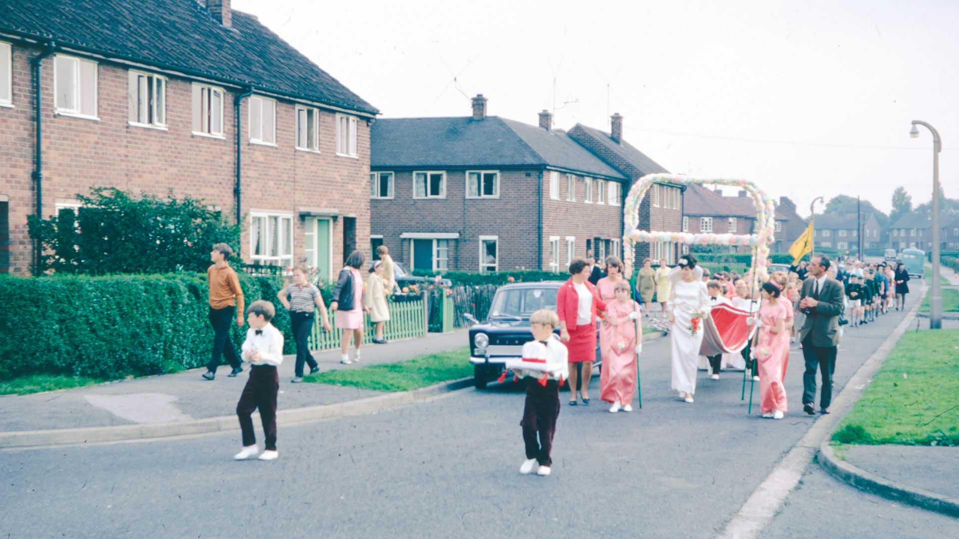 People parade down a street, dressed in white clothing.