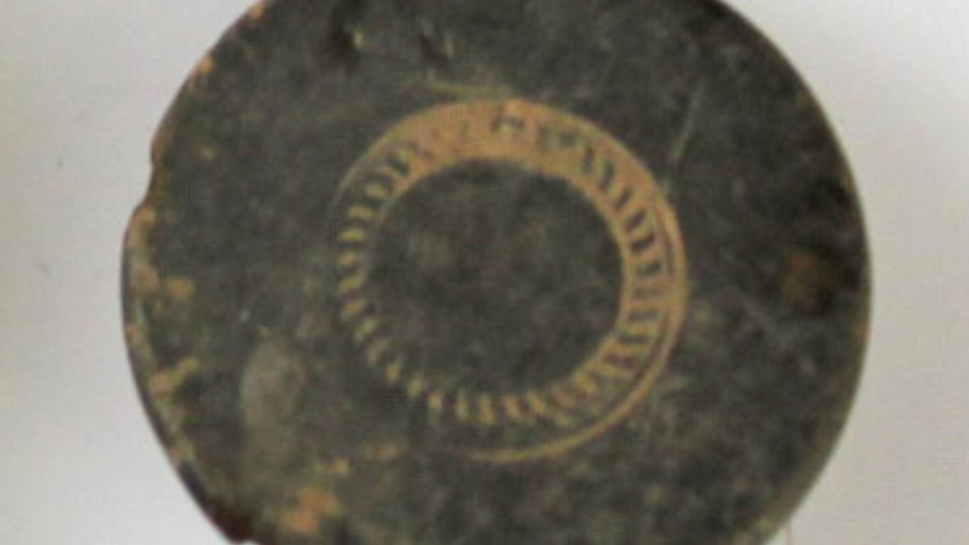 A postmedieval copper alloy (tombac) button measuring 16mm in diameter. The button is circular and is decorated on the front with two concentric circles; the space between the two circles is filled with a pattern of small lines. The button dates to the 18