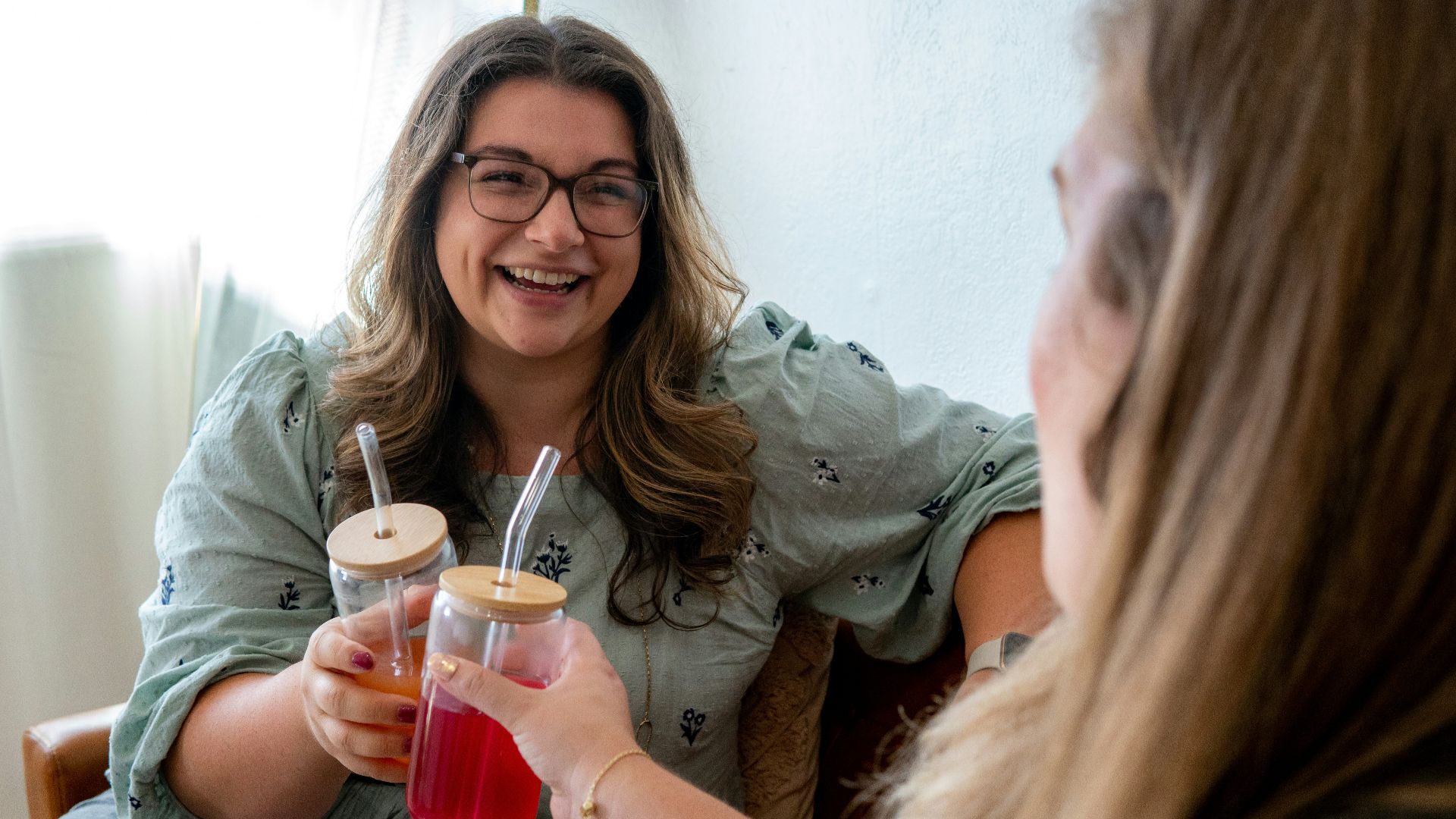 a woman holding a drink and a woman holding a glass with a straw