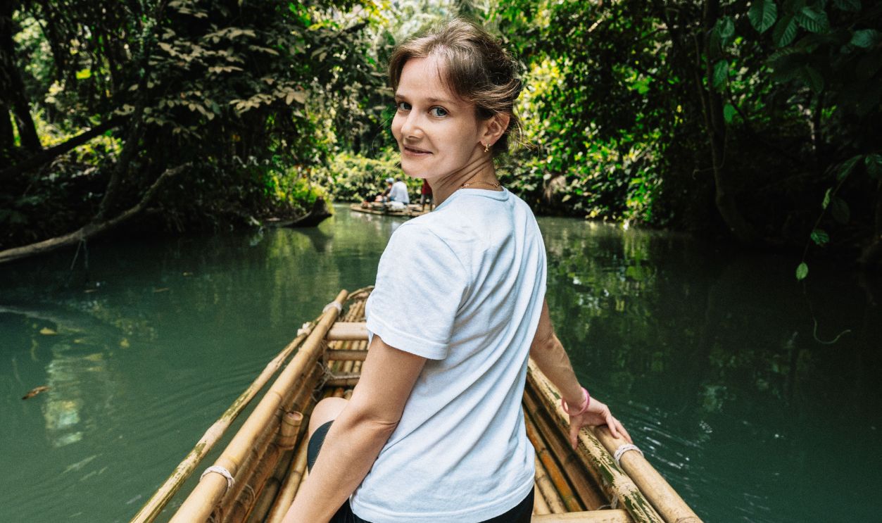 A woman enjoys a scenic ride on a bamboo raft