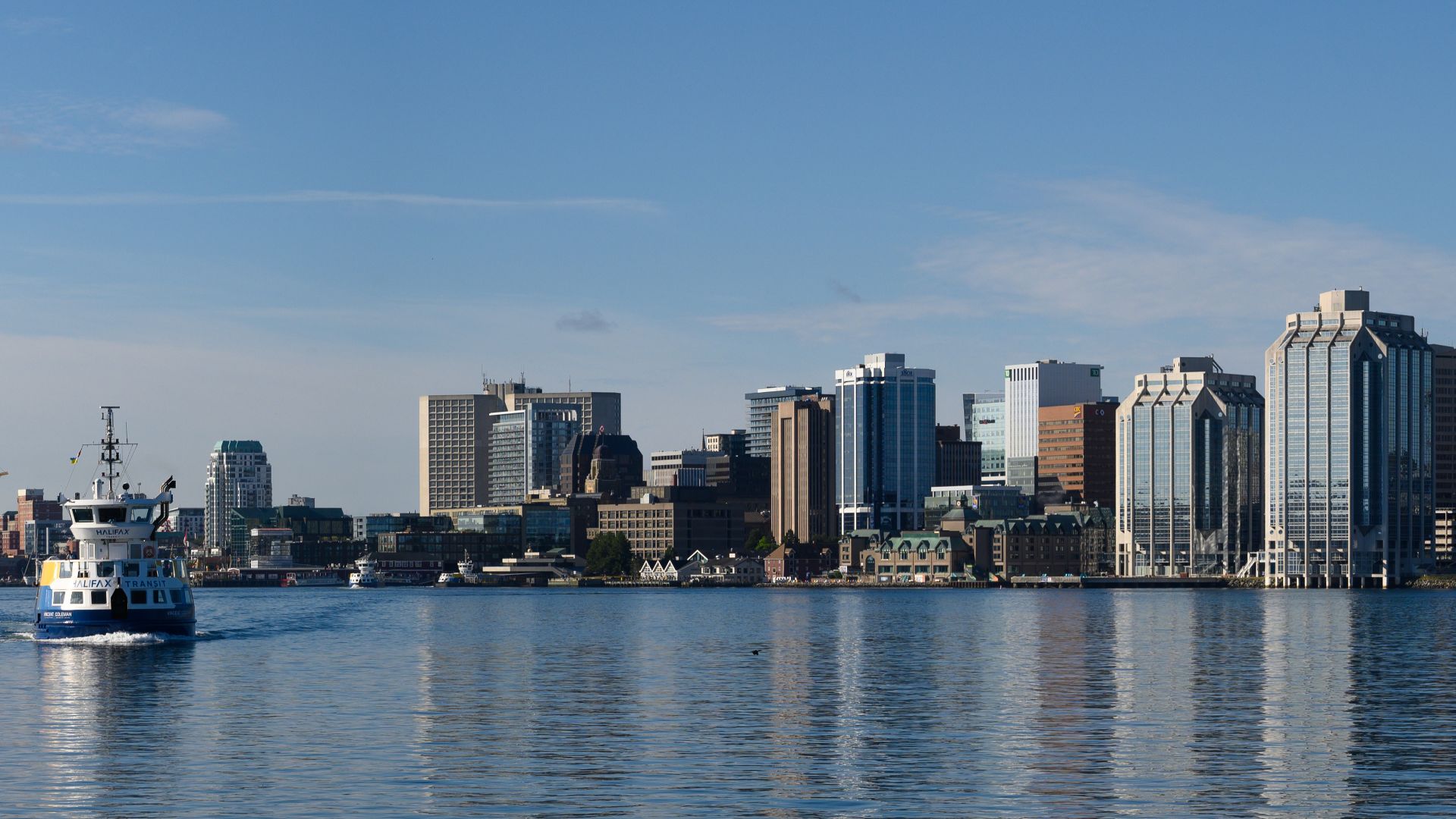 View of downtown skyline at Halifax, Nova Scotia, Canada on July 21, 2022. Halifax Transit ferry, VINCENT COLEMAN - IMO 9850317, at left, is heading towards Dartmouth Alderney terminal.