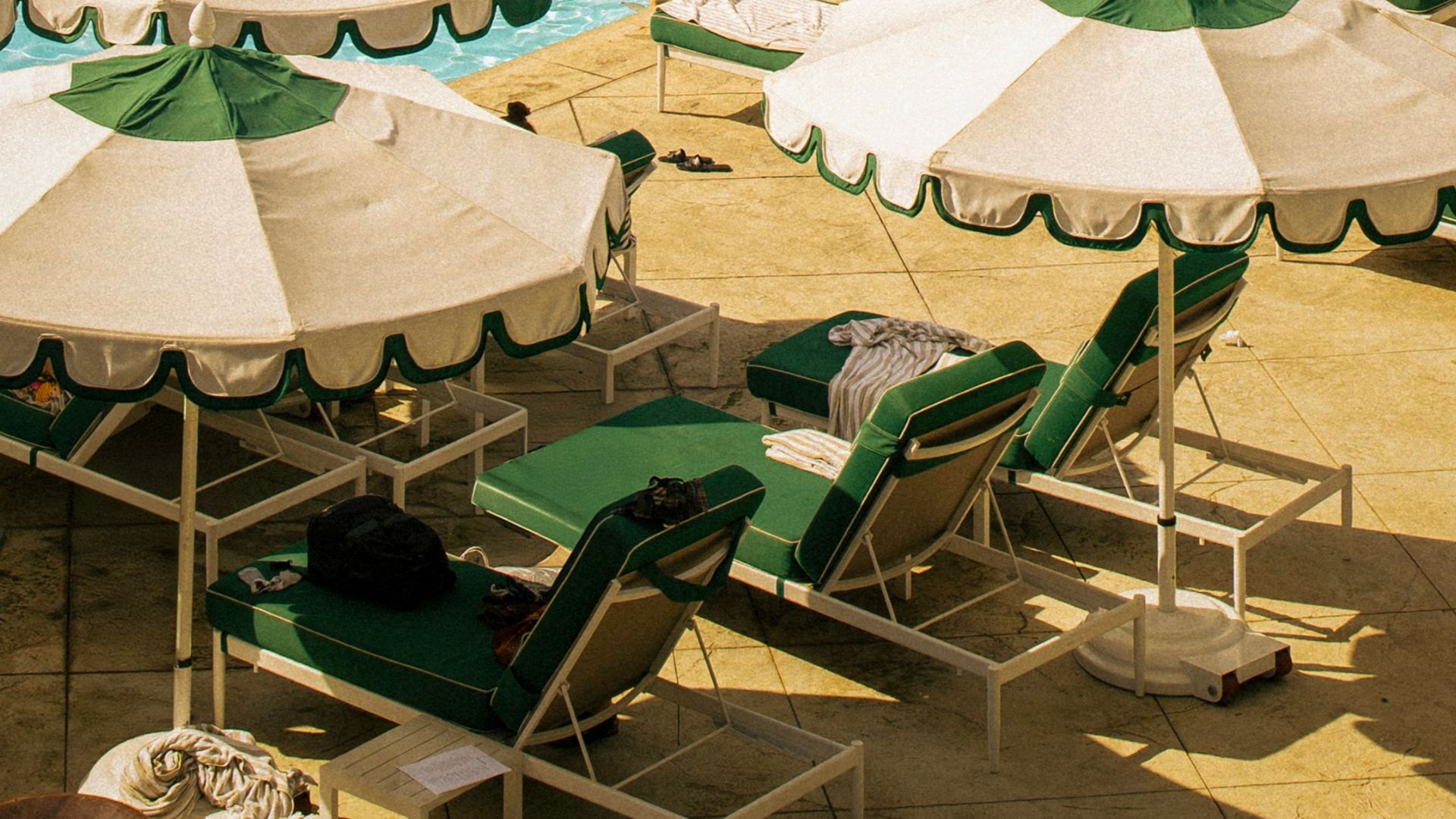 Resort pool with lounge chairs and umbrellas on sunny day.
