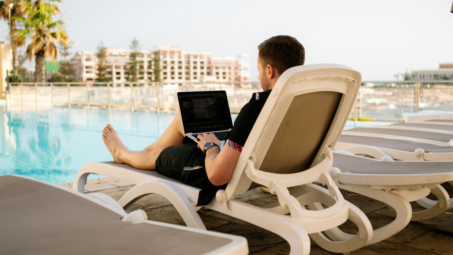 man on sun lounger using laptop