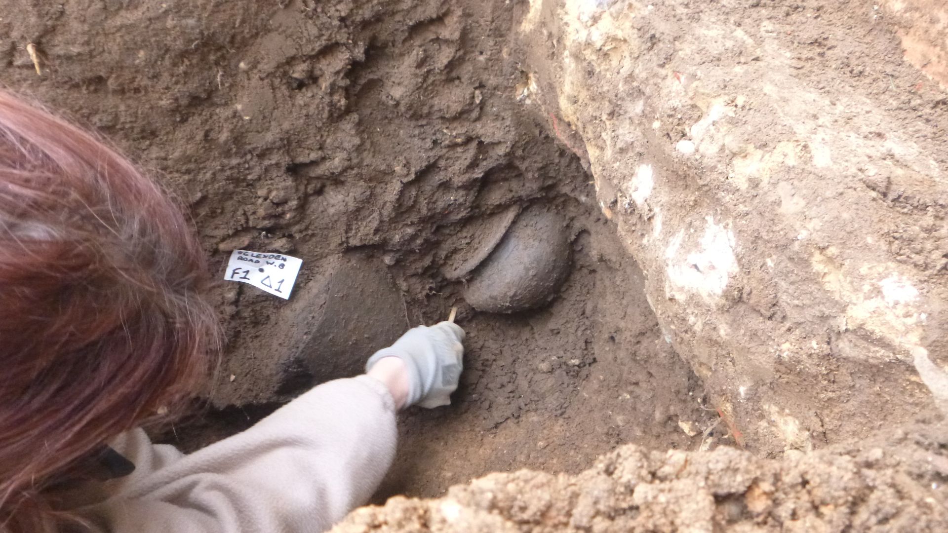 Archaeologists excavating a ceramic at 86 Lexden Road, Colchester, Essex, January 2023