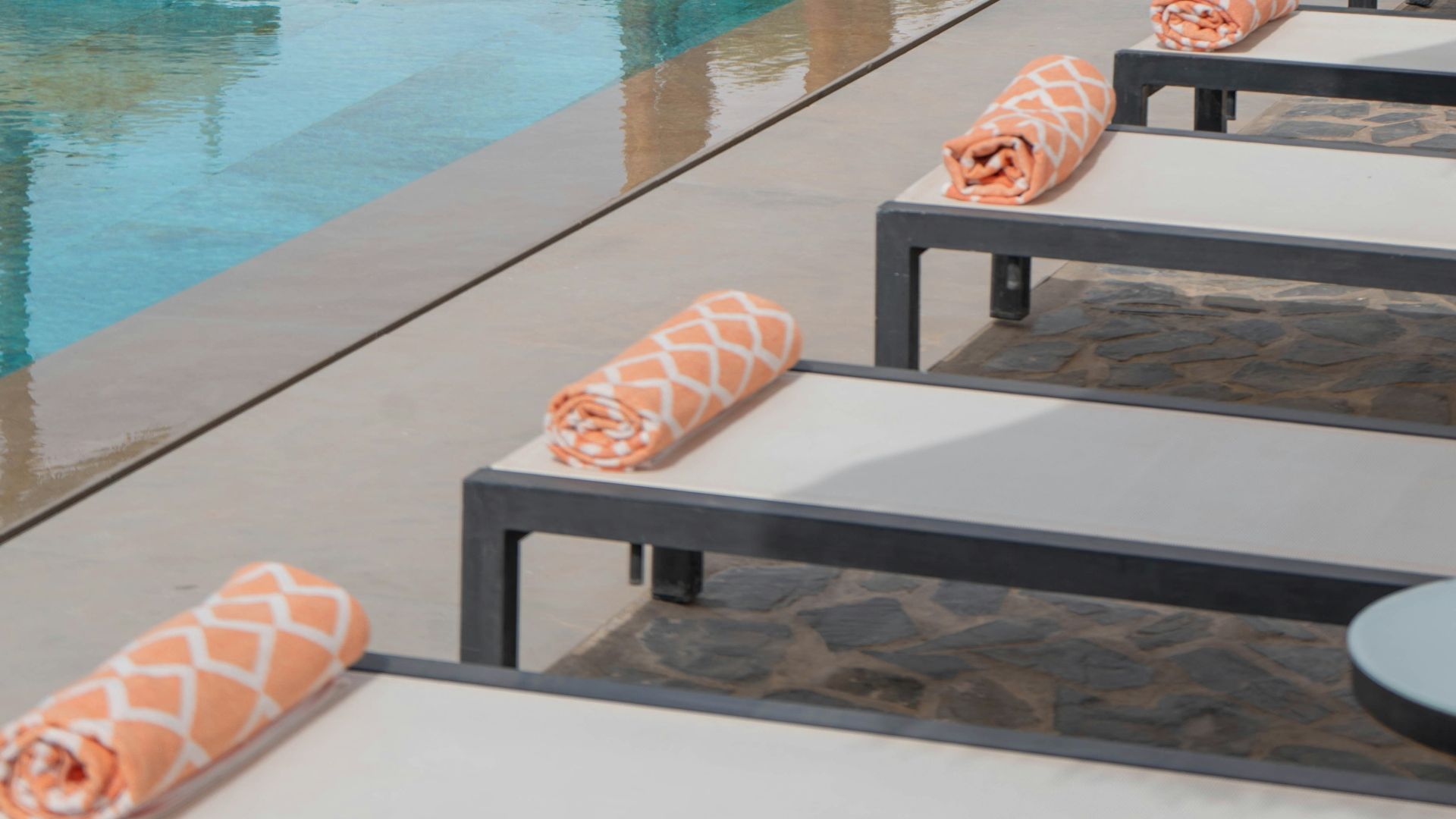 Lounge chairs with towels beside a swimming pool.