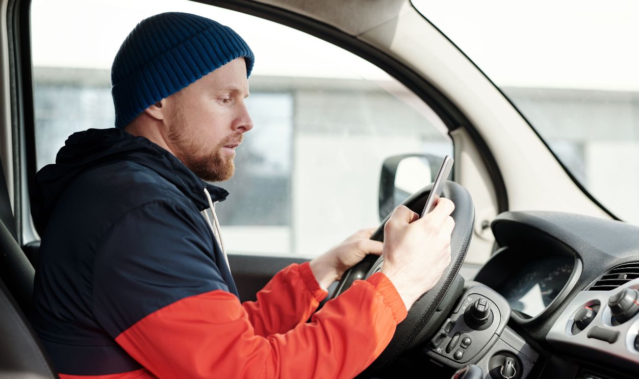 Distracted driver uses a smartphone in a car, highlighting road safety