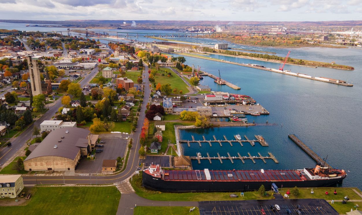 This aerial photo showcases the Soo Locks in Sault Ste Marie, Michigan, on a partly cloudy autumn day, providing a unique perspective of the lock systems and surrounding fall foliage, October 16, 2022