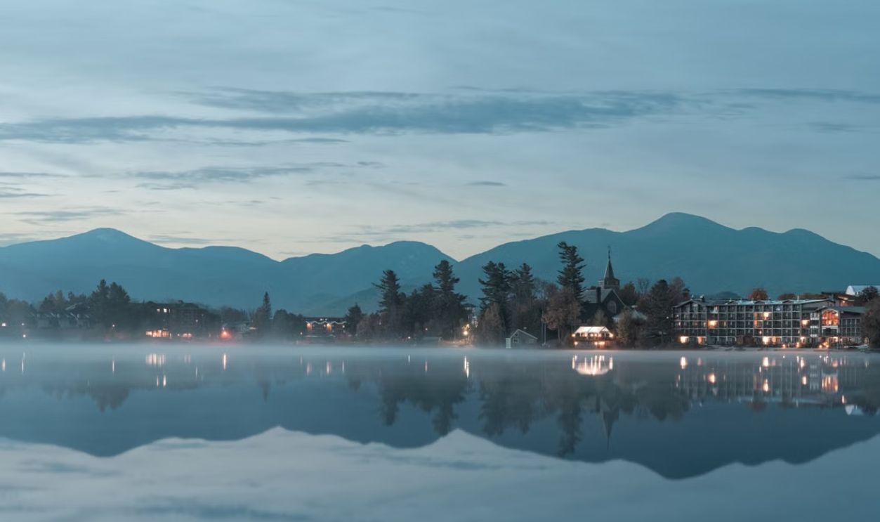 Tranquil morning view of Lake Placid with misty reflections and distant Adirondacks