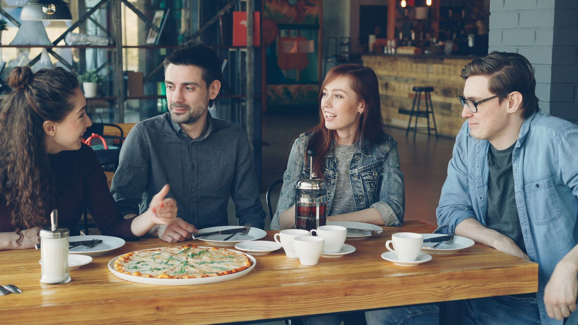 Friends enjoy pizza and conversation in a restaurant.