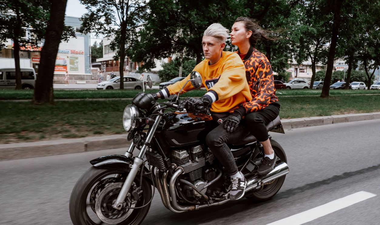 Stylish couple traveling on a motorcycle through a city street 