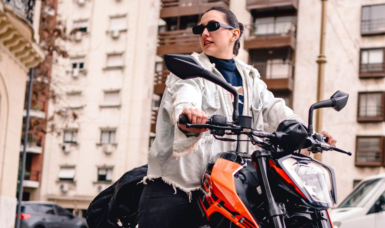 Confident woman in sunglasses riding motorcycle in vibrant city 