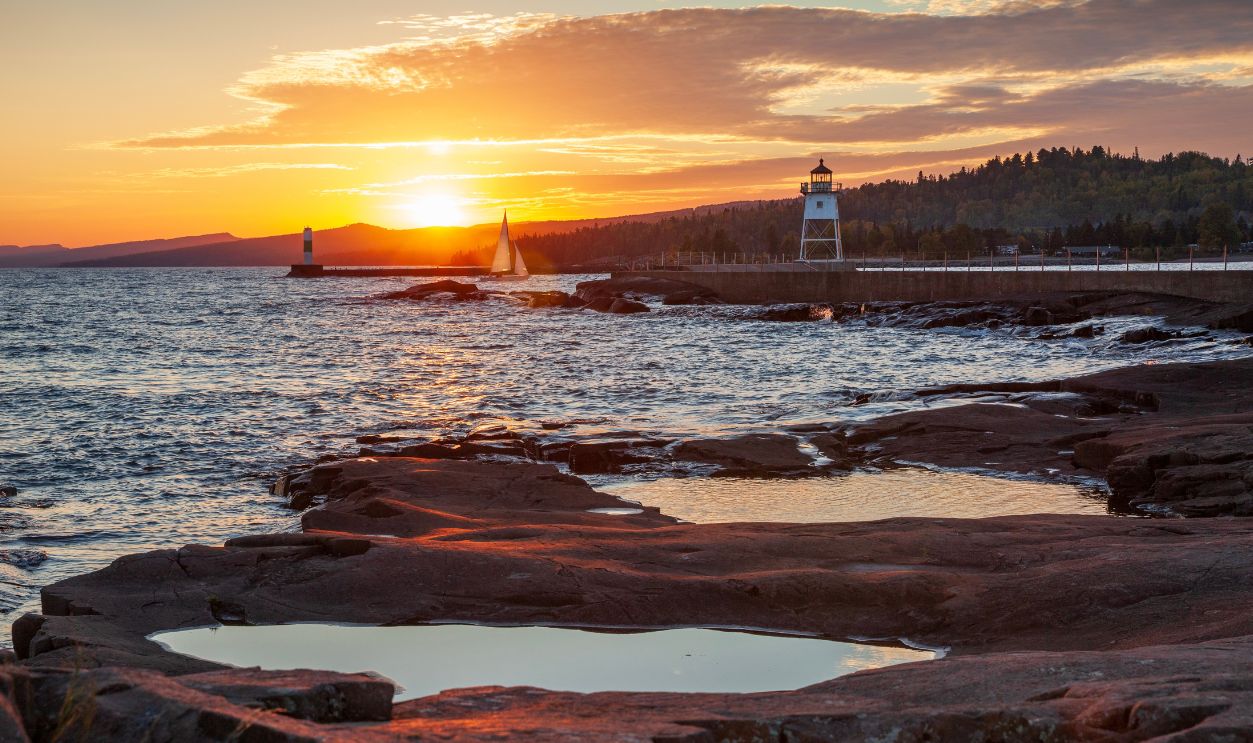 Sailboat entering the harbor at Grand Marais viewed from Artist's Point at sunset on an autumn day