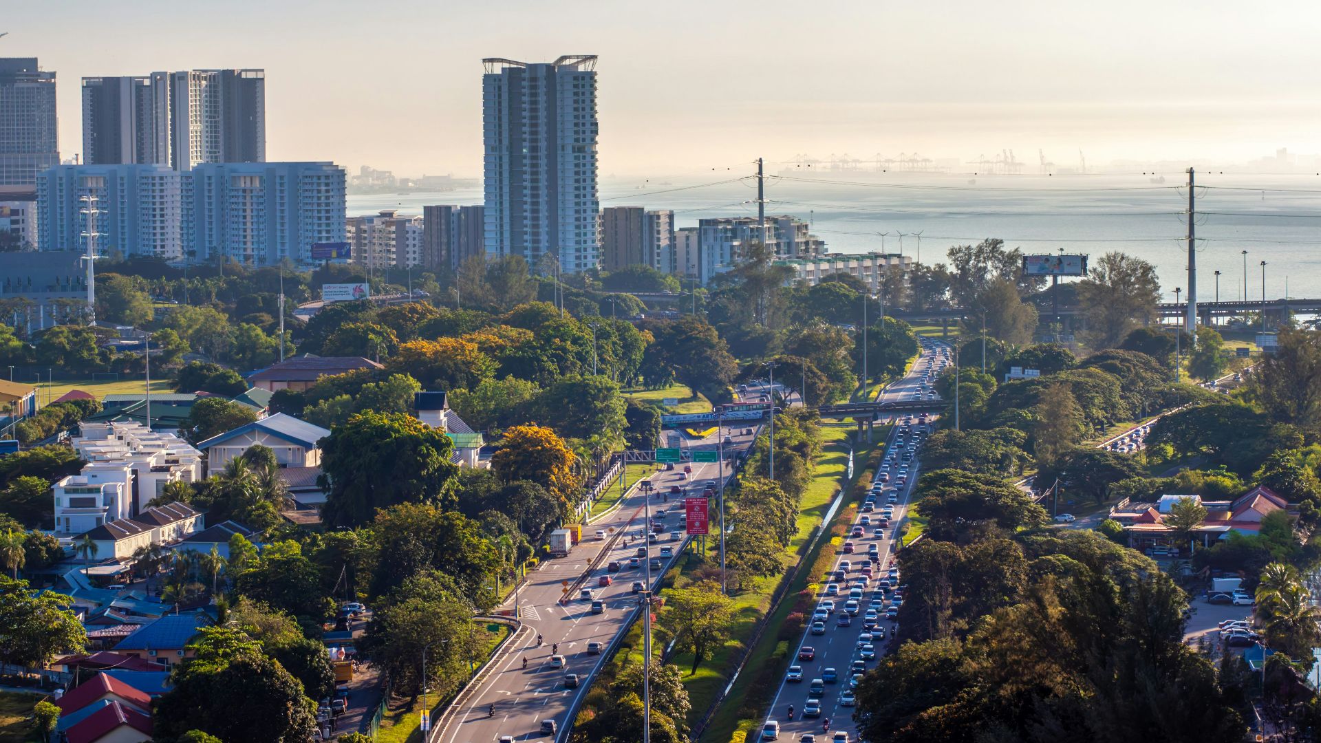 Cityscape with buildings, highway, and a sea view.