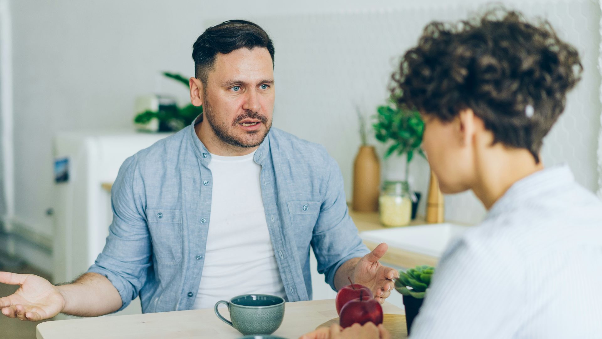a man sitting at a table talking to a woman