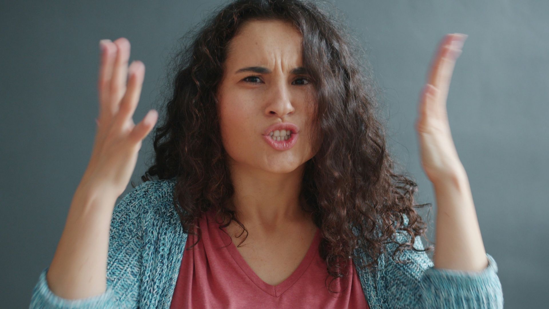 Woman with curly hair looking angry and frustrated.