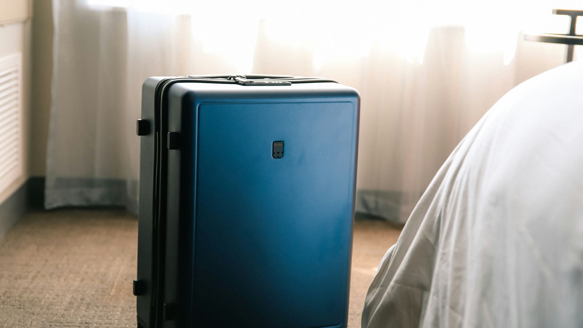 a blue suitcase sitting on the floor next to a bed