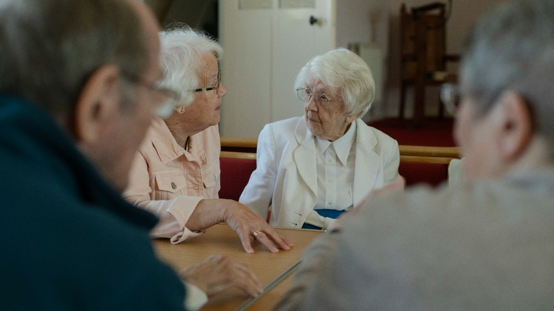 Seniors are sitting around a table, talking.