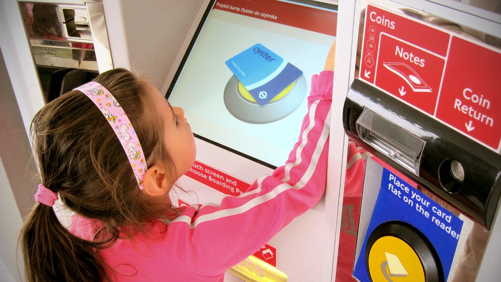 Girl using Oyster card top-up machine at Emirates Royal Docks (London).