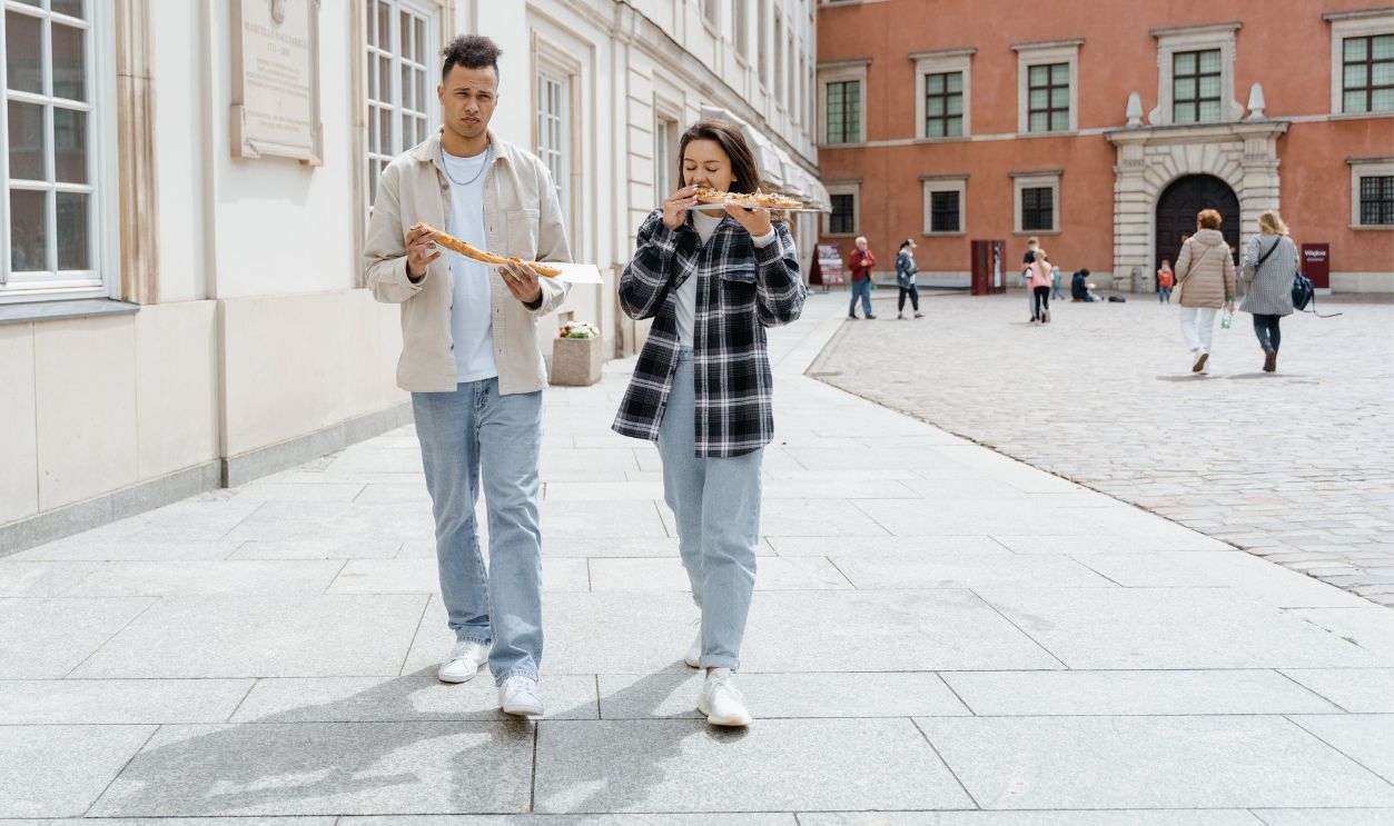 A couple walking in an urban area, enjoying a fresh baguette